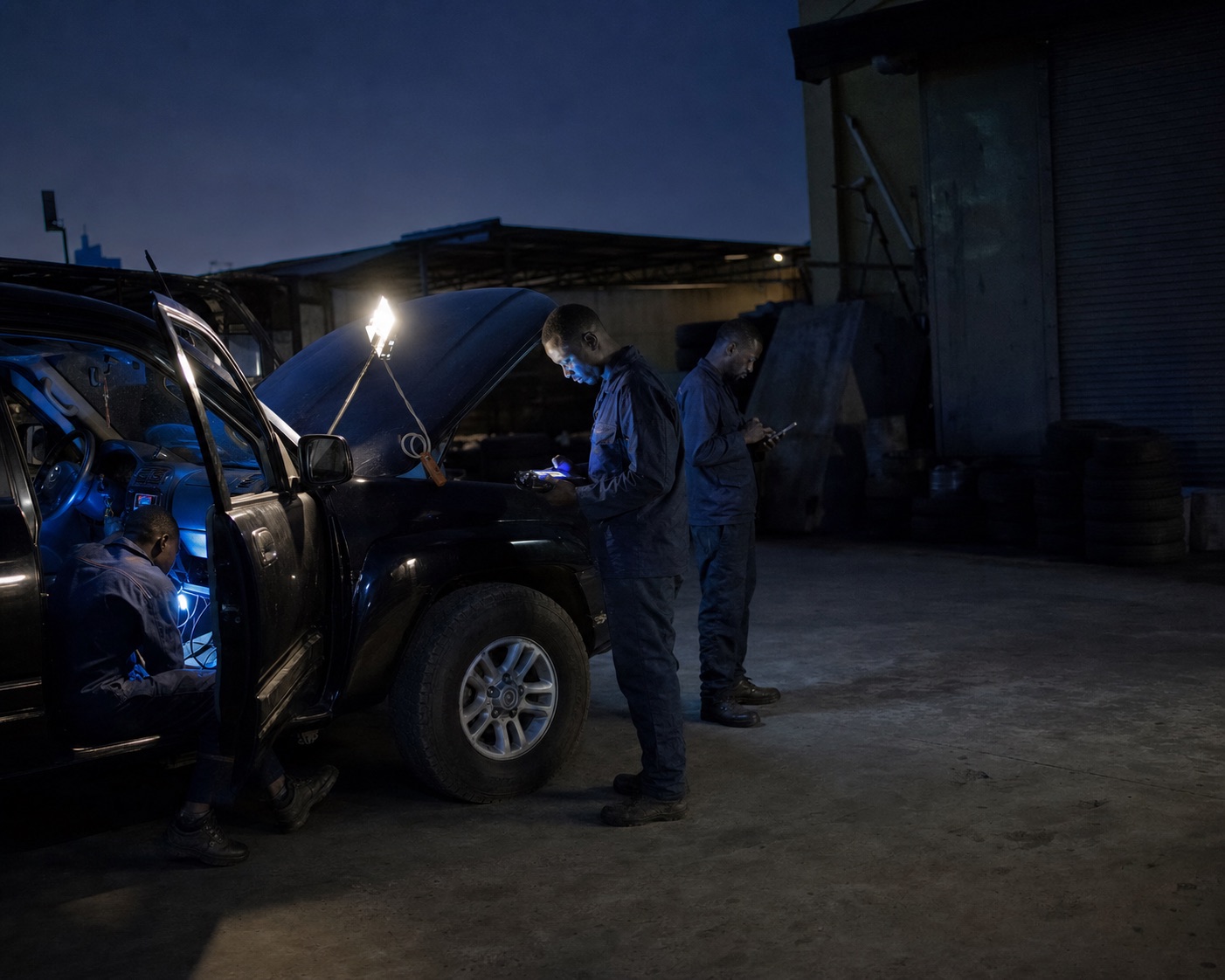 Three GT AFRIK technicians installing tracking equipment in a vehicle at a Kinshasa depot